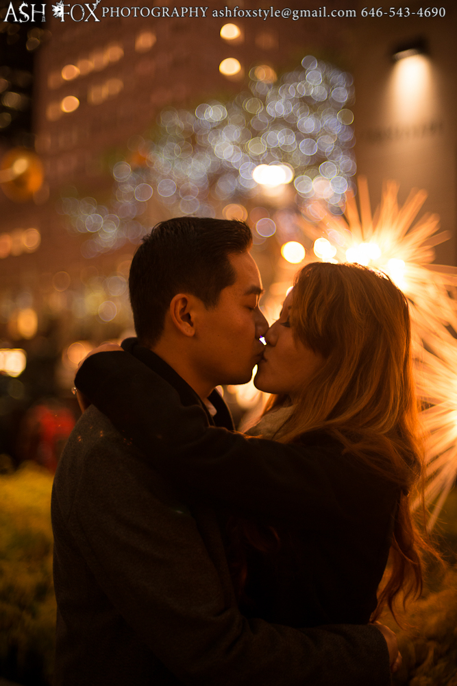 Kissing after a proposal at Rockefeller Center with cool Christmas Holiday lights in the background