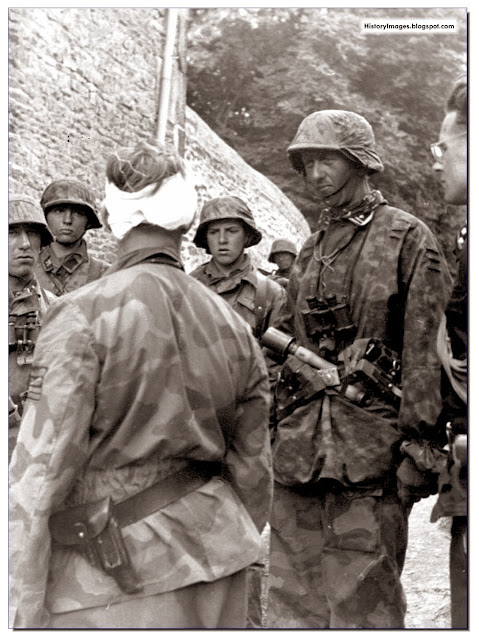 Waffen SS Colonel Max Wunsche, commander of the 12th SS Regiment of the Hitlerjugend Division (bandaged head) with men of the 25th regiment of the SS at Po (village in France) on June 9, 1944. Partly seen on the right side of the image is Rudolf, son of German foreign minister von Ribbentrop