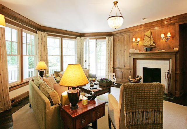 wood paneled family room/library with traditional decor, a fireplace and a pendant light