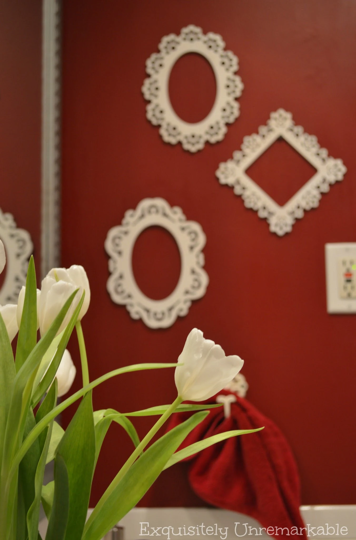 White wooden frames on a red painted wall with tulips in the foreground