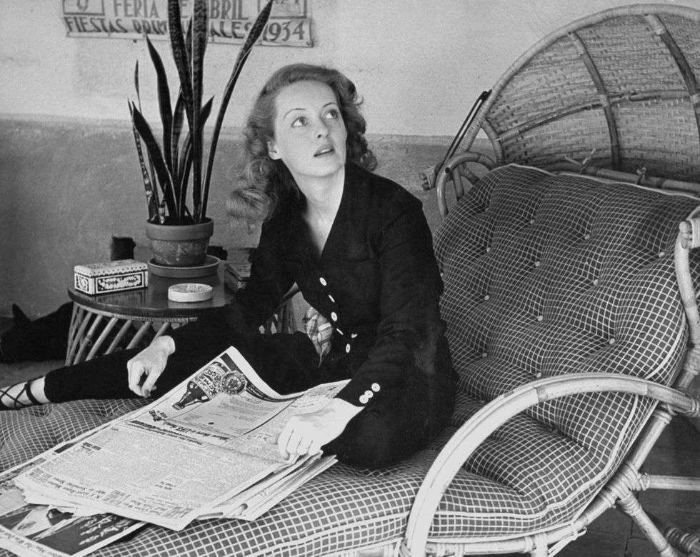 Bette Davis relaxing with the morning papers at her home in 1939