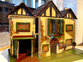 Front view of a vintage doll's house displayed in a museum.