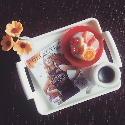 Flat-lay instagram photo of a dolls' house miniature tray holding a copy of Renegade Collective magazine, a vase of flowers, a fruit danish on a plate and a mug of coffee.