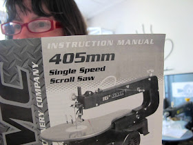 Woman reading an instruction manual for a scroll saw.