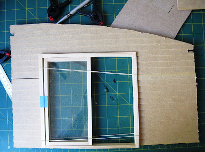 Wall of a dolls' house kit, with weatherboarding cut to size and a sliding door dry fitted.