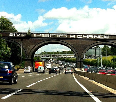 London M25 sign Give Peas A Chance