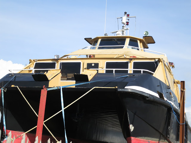 Boat with faded paint in boatyard under repair.