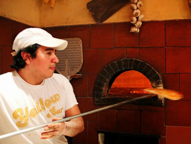 cooking pizza in a wood fired brick oven by cook