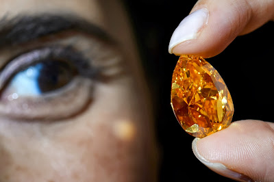 A model shows "the Orange" a 14.82-carat pear-shaped, vivid orange diamond during a press preview on October 31, 2013 in Geneva. The largest known orange diamond in the world will be auctioned by Christie's in the Swiss city of Geneva on November  2013, is expected to fetch between between 12,5 and 15 million euros (17 and 20 million US Dollars)