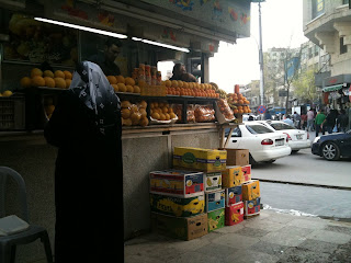 a woman standing outside a fruit stand