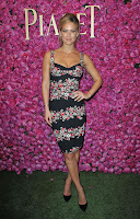 Bar Refaeli on the green grass carpet and standing in front of a pink rose wall