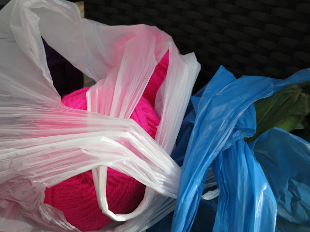 Pink knitting yarn in white plastic bag. Leeks in blue plastic bag.