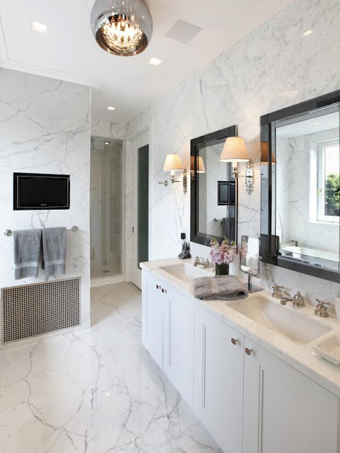 white marble master bathroom in an apartment with built in white cabinets, black mirrors and undermount sinks