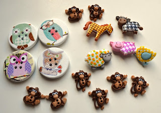 A collection of 'animal buttons'. At the top and bottom are 2-holed buttons of brown monkeys, some in a sitting position and others in a climbing position. On the left hand side is a set of four 3 cm 4-holed round buttons painted with owls. On the right is a collection of farmyard animal shank buttons - clockwise from top right, black and white houndstooth cow, yellos and white polka-dotted chick, pink and white diamond patterned pig, sheep with a grey face and feet with yellow daisies on the fleece, and a yellow and brown gingham horse!
