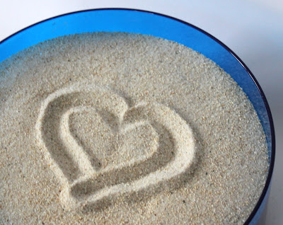 blue bowl of sand. heart drawn in sand