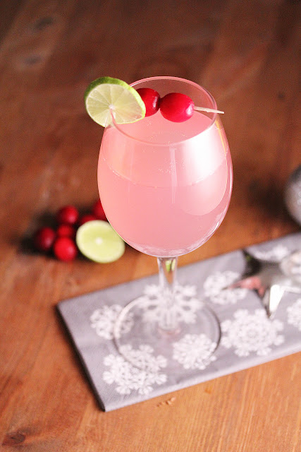 Cranberry Ginger Fizz in a wine glass with fresh lime and cranberry garnish