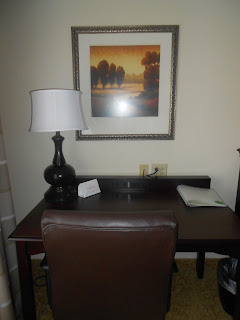 a desk with a lamp and a picture on the wall