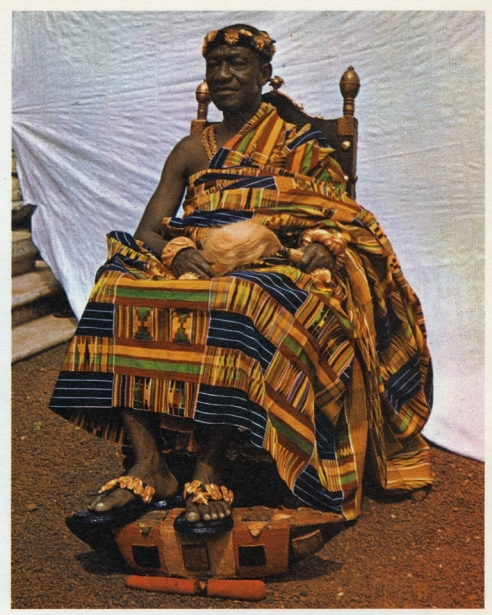Otumfuo Sir Osei Agyeman Prempeh II, K.B.E. wearing his special regal kente (circa 1930). Asantehene, occupant of the Golden Stool.... He is seated on one of his ceremonial chairs, the ankaahono, decorated with a gold design of sliced oranges