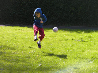 boy kicking football off the ground
