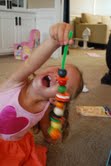 little kid making a caterpillar with beads and a pipe cleaner