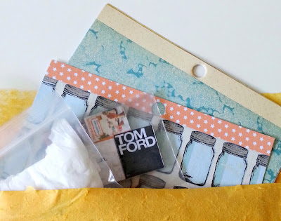 Selection of small scrapbooking paper pages, miniature books and a wrapped parcel peeking out of a bubble bag.