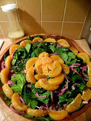 Salad arranged in large wooden bowl sprinkled with sesame, with dressing on side