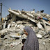 A Palestinian woman walks past the rubble of a residential building, which was destroyed in an Israeli air strike 