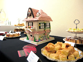 Table of slices with a dolls'-house shaped cake in the middle.