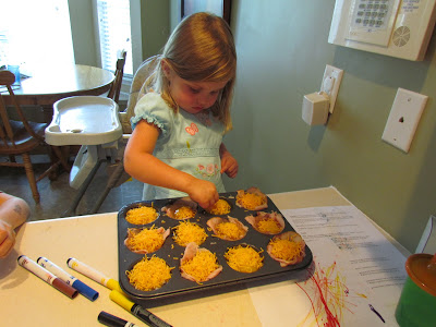 child helping put cheese in a muffin tine