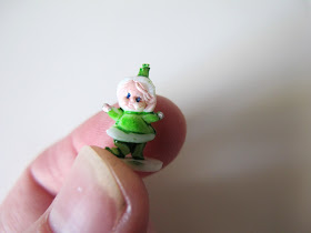 Tiny dolls' house miniature gnome ornament, being held between a finger and a thumb.