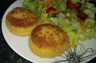 A plate with two freshly made salmon fishcakes accompanied by a fresh salad. Delicious.