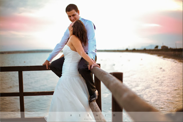 novios sentados en el mirador de madera que sobresale del mar