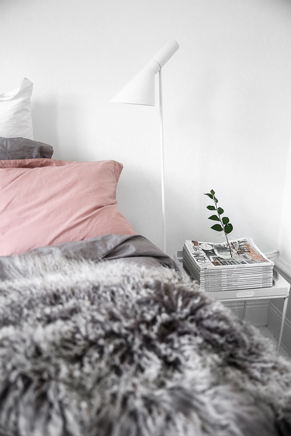 Cozy scandinavian bedroom with pink bedding and grey fur throw. Image by Kiki via Damernas Värld