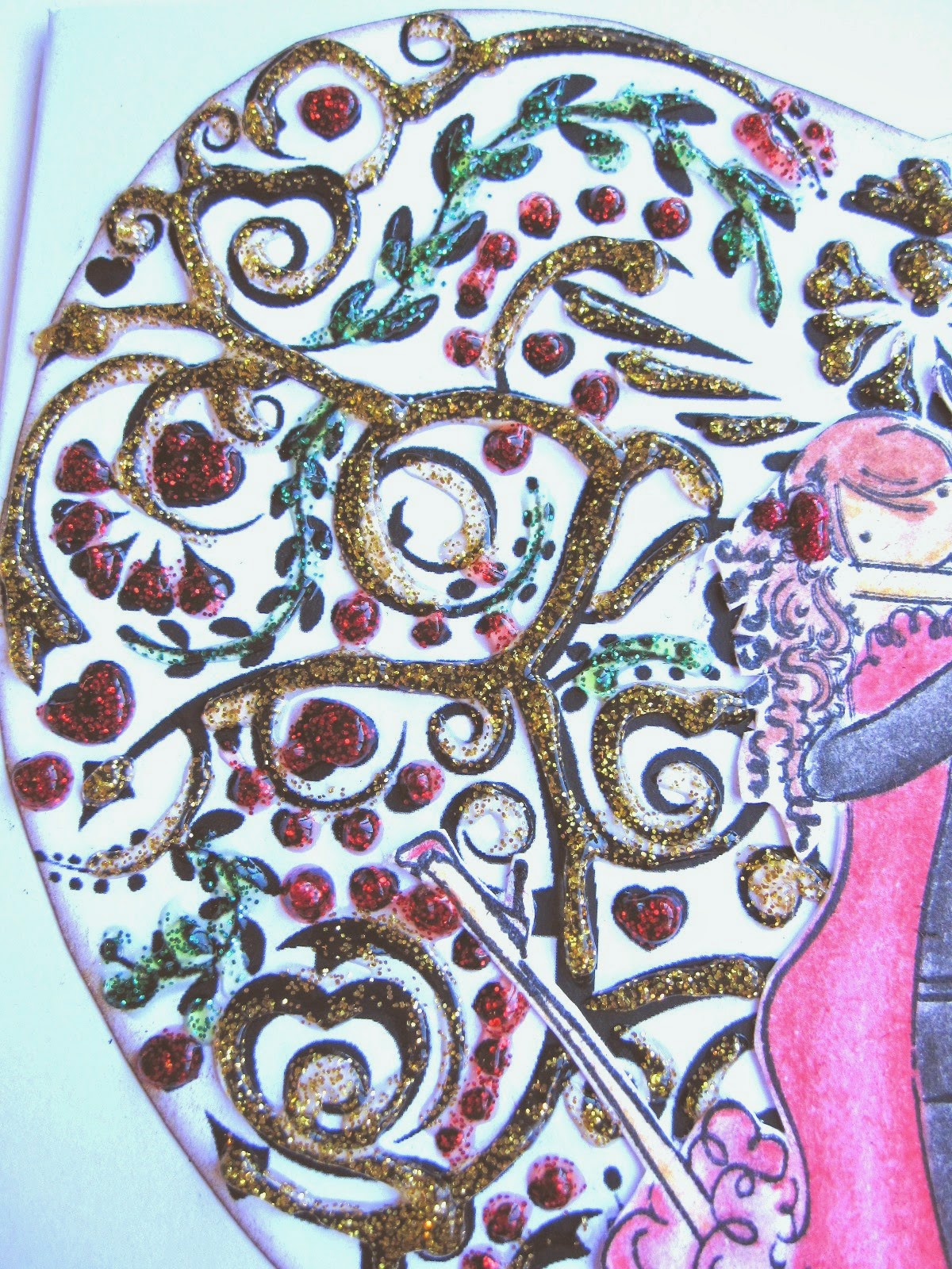 detalle de tarjeta de scrapbooking para San Valentín con corazón de filigrana decorado con glitter glue rojo, verde y amarillo