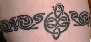 A colour photo of my tattoo, a celtic knot surmounted by a little dragon's head and on either side an interlocking swirling pattern.