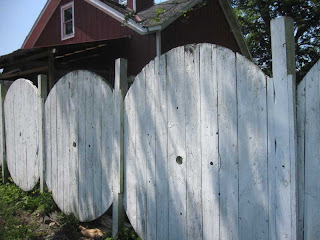 Tops and bottoms of large spools used as fence panels with posts between
