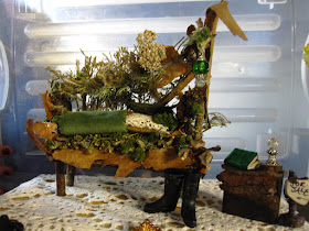 A miniature fairy sofa covered in leaves and plants.