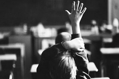 Child raising hand at desk