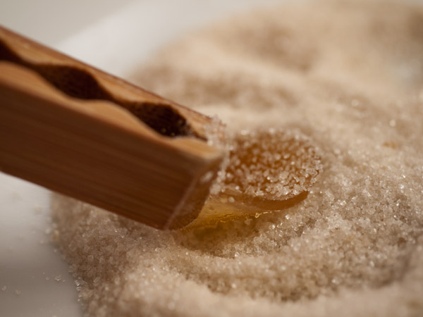 Candied ginger being dipped in sugar with bamboo tongs