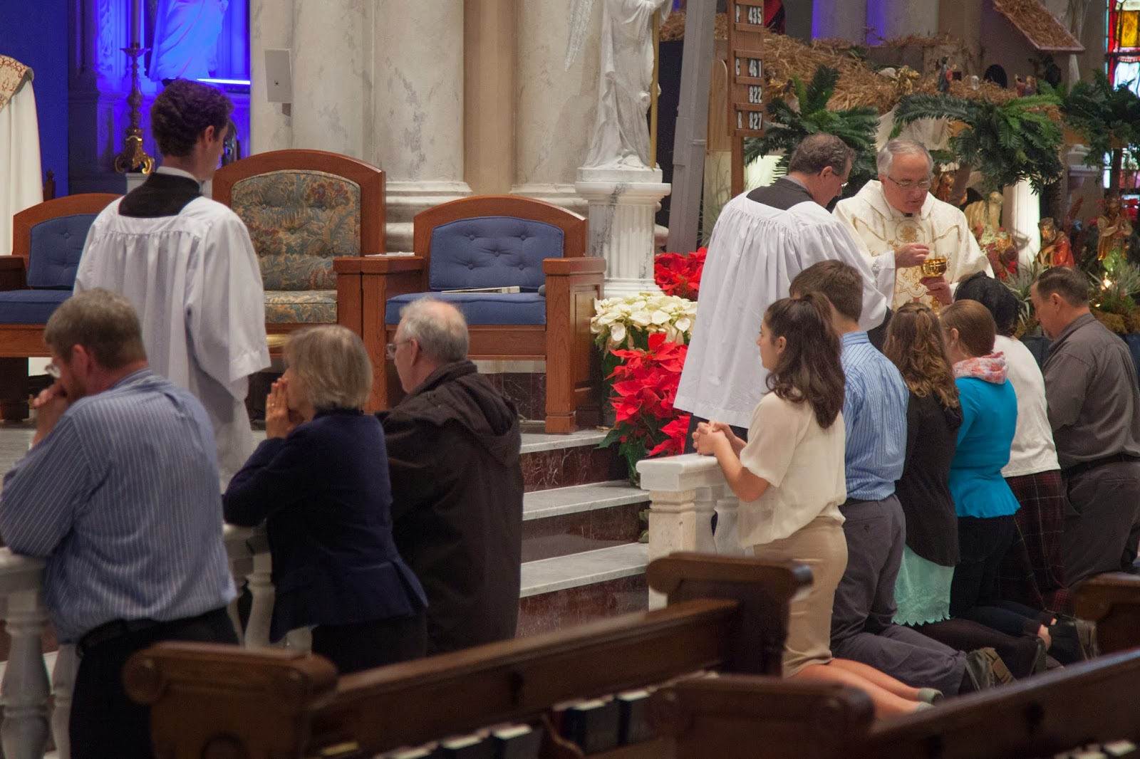 The faithful kneeling at the altar rail during the distribution of Holy Communion.