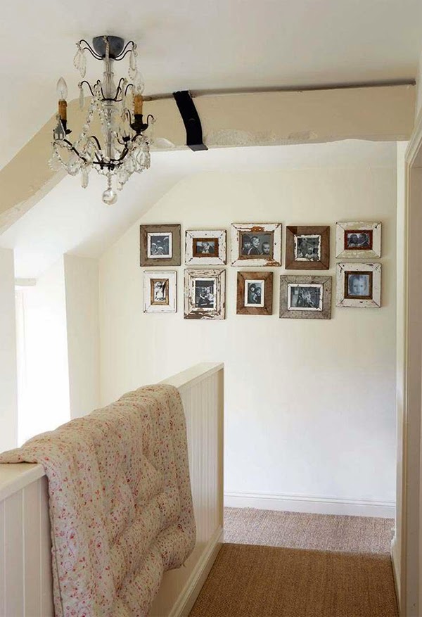 Cottage chic landing with vintage paisley eiderdown and nicely arranged photo frames on the wall