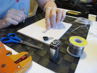 Woman sticking a run of copper tape to a tile.