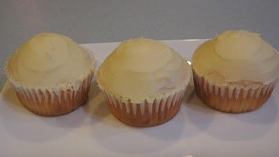 three cupcakes with white frosting on white plate