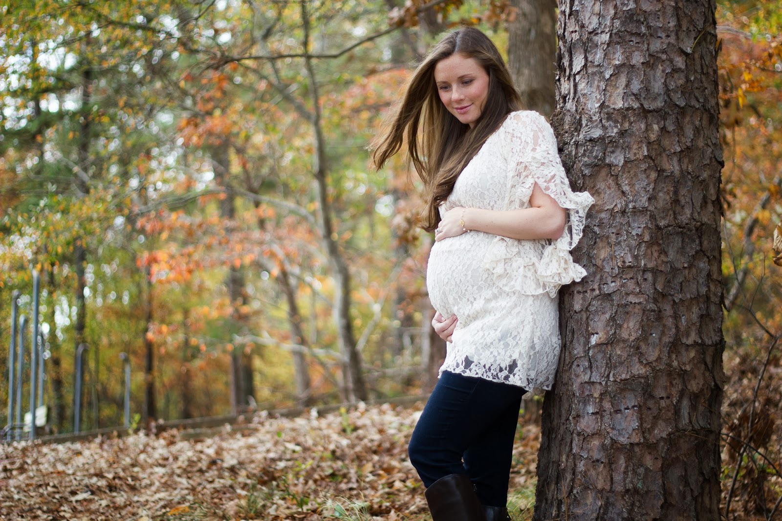 fall maternity shoot mom wearing lace dress and knee high boots at park