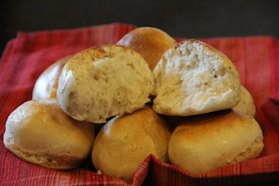 dinner rolls in a basket with one broken in half