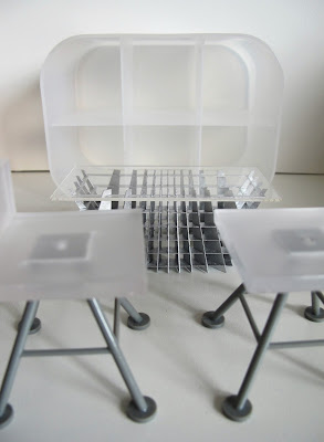 Two modern dolls' house miniature white and grey bar stools from the Kaleidoscope House, a SLICE Tilt coffee table. and a white perspex shelving unit.