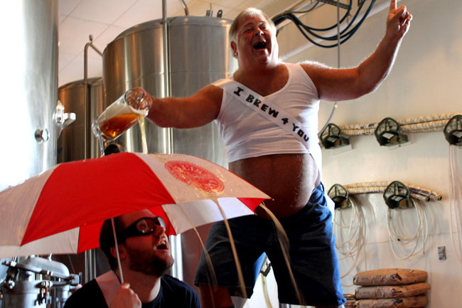 Witziger Mann mit Bierbauch - Bier über Regenschirm giessen