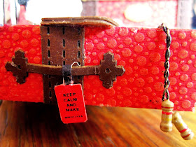 Miniature red trunk with skipping rope hanging over the edge and tag which reads 'Keep calm and make miniatures'