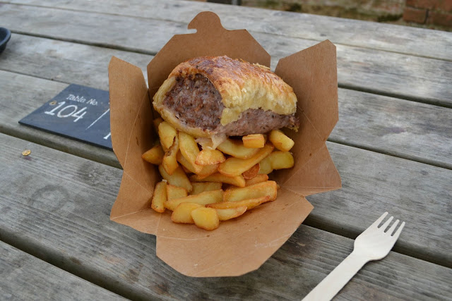 A large sausage roll on top of a pile of chips