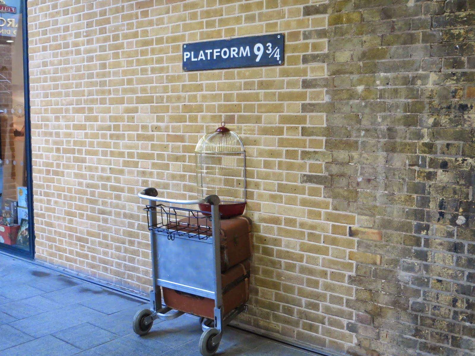 Plataforma 9 3/4 com o carrinho de Harry Potter com suas malas e gaiola de coruja, localizada em London King's Cross 